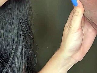 Förförisk brunett i röda spetsunderkläder och blå naglar ger en sensuell avsugning