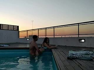 Et spændende møde i poolen under solnedgang for en revisor med en stor pik og en smuk partner